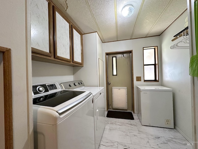 laundry area with cabinets, a textured ceiling, and washing machine and dryer