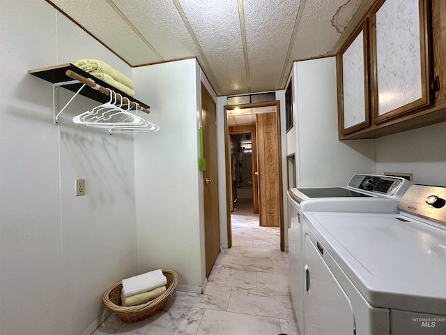 laundry room featuring washer and clothes dryer, cabinets, and a textured ceiling