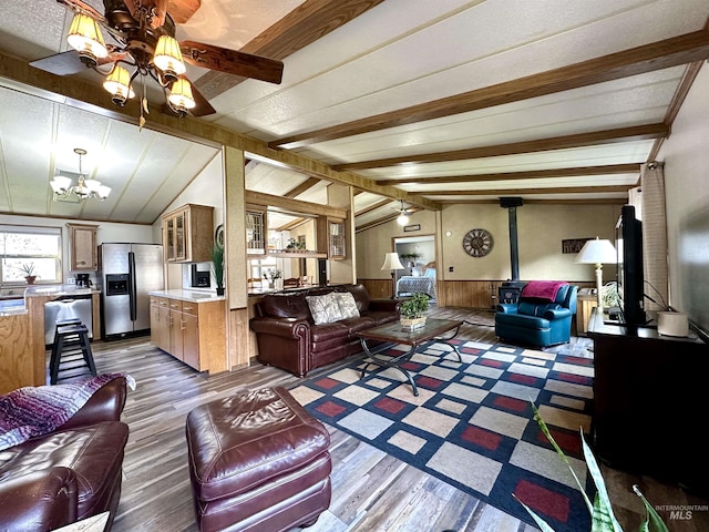 living room featuring vaulted ceiling with beams, dark hardwood / wood-style flooring, a wood stove, and an inviting chandelier