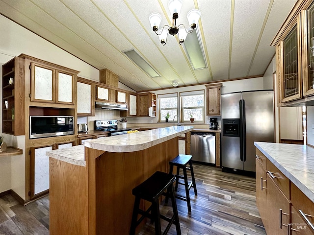 kitchen featuring pendant lighting, a center island, a kitchen bar, dark hardwood / wood-style flooring, and stainless steel appliances