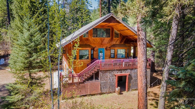 rear view of property with stairway, a forest view, and a porch