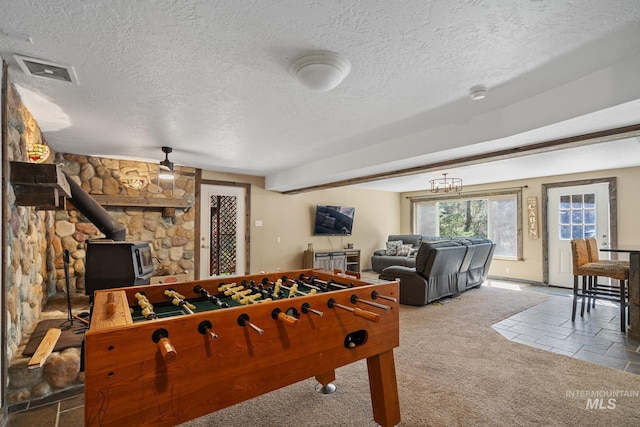 game room with a wood stove, a textured ceiling, carpet floors, and baseboards
