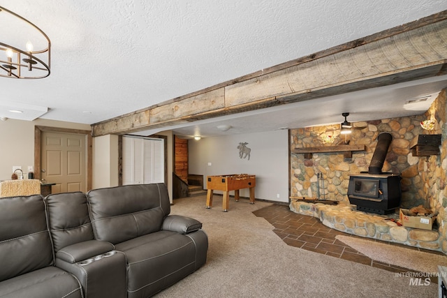 carpeted living area featuring a wood stove, a textured ceiling, and baseboards