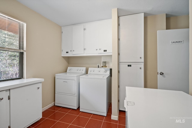 laundry room featuring washing machine and dryer, cabinet space, dark tile patterned floors, and baseboards