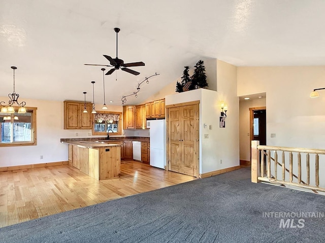 kitchen featuring plenty of natural light, a peninsula, vaulted ceiling, and white appliances