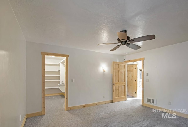 carpeted spare room with baseboards, a ceiling fan, and visible vents