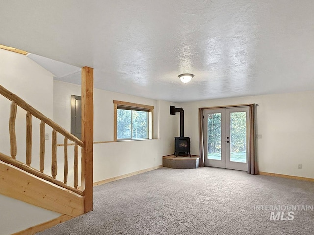 unfurnished living room featuring french doors, a wood stove, and carpet floors