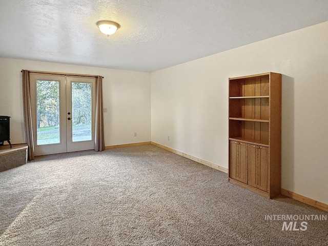 unfurnished room featuring a textured ceiling, baseboards, light colored carpet, and french doors