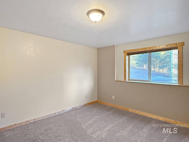 carpeted spare room featuring baseboards and a textured ceiling