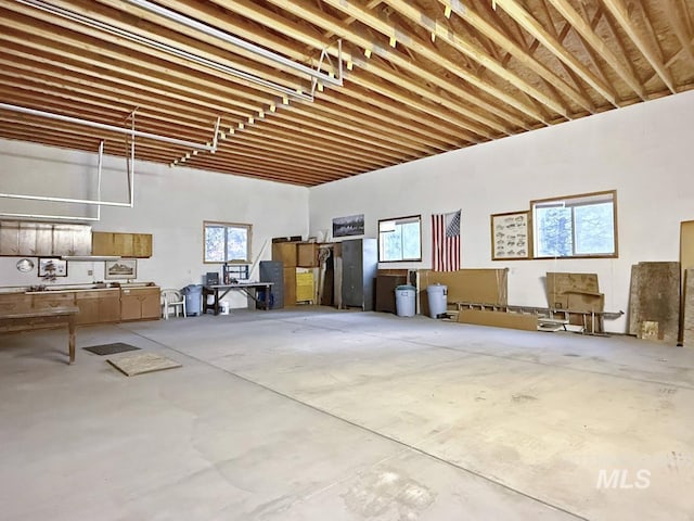 misc room with a healthy amount of sunlight, a high ceiling, and concrete flooring