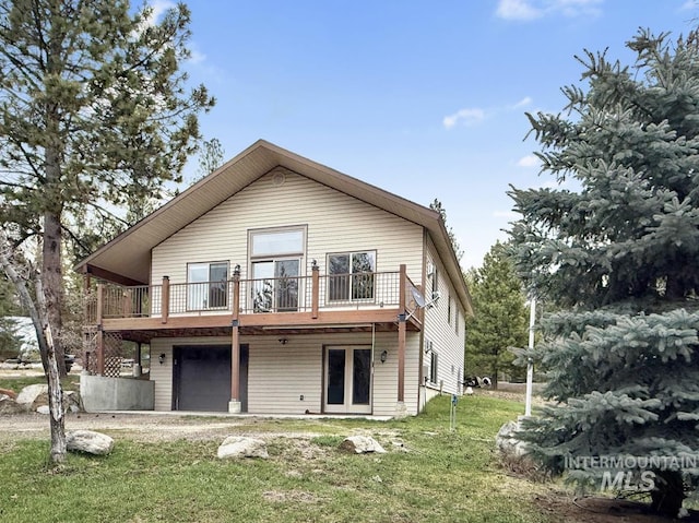 rear view of house featuring a garage, a yard, a deck, and french doors