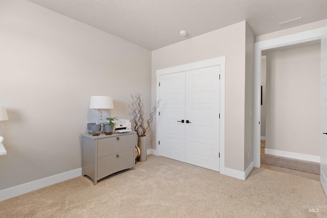 bedroom with a closet, light colored carpet, and baseboards