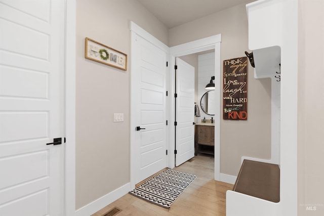 hallway featuring light wood finished floors and baseboards