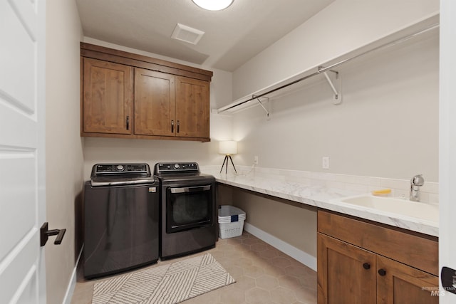 washroom featuring a sink, visible vents, baseboards, washer and dryer, and cabinet space