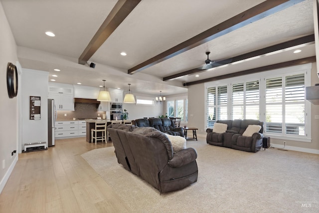 living room featuring recessed lighting, baseboards, beam ceiling, and ceiling fan with notable chandelier