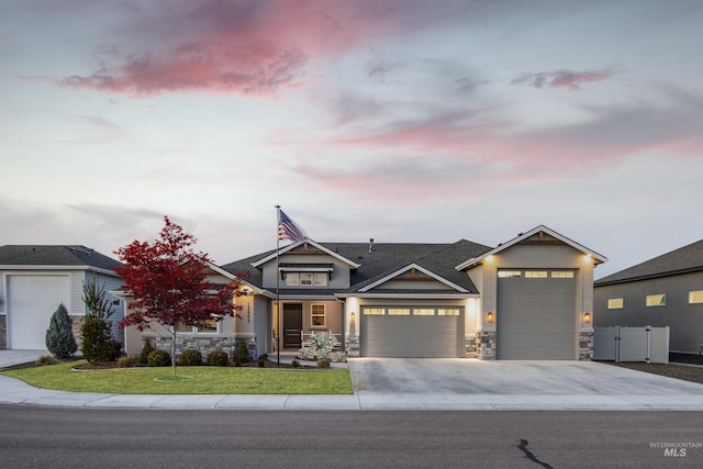 view of front of house with stone siding, a lawn, an attached garage, and concrete driveway