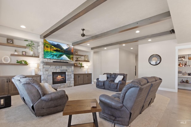 living room with baseboards, beamed ceiling, a stone fireplace, built in shelves, and recessed lighting