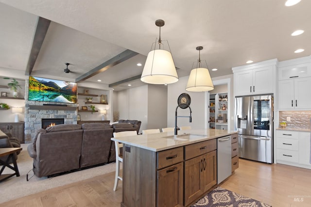 kitchen with appliances with stainless steel finishes, a sink, white cabinets, and light wood-style floors