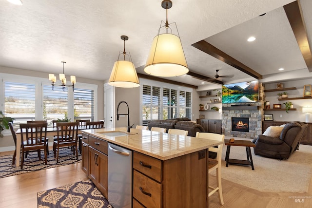 kitchen with dishwasher, a textured ceiling, a sink, and light wood finished floors