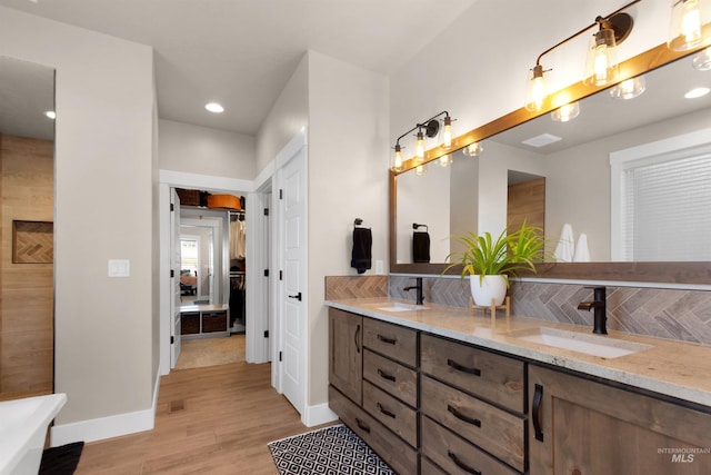 bathroom featuring double vanity, a sink, baseboards, and wood finished floors