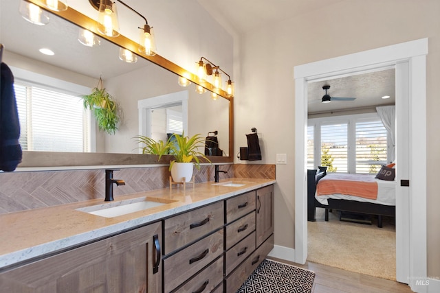 ensuite bathroom featuring double vanity, tasteful backsplash, baseboards, ensuite bathroom, and a sink