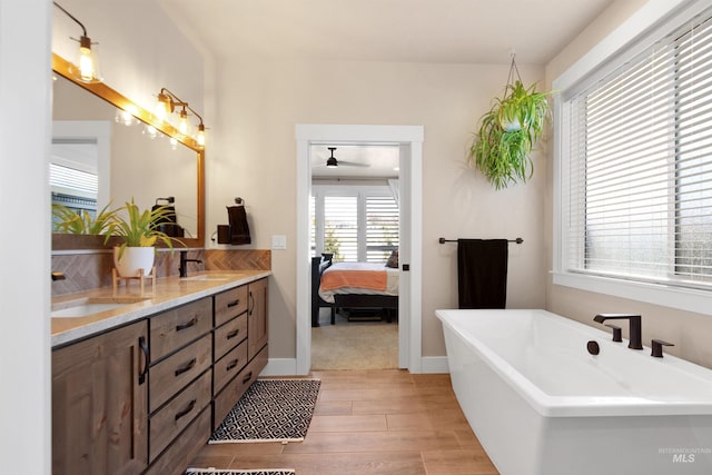 bathroom featuring a freestanding bath, double vanity, wood finished floors, and a sink