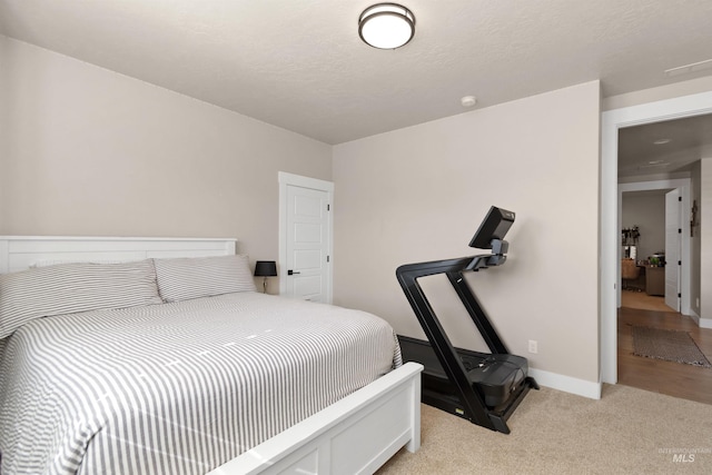 bedroom with light carpet, a textured ceiling, and baseboards