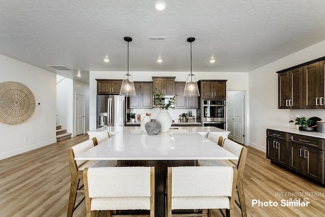 5543 E Bridal Veil Falls Dr, Nampa, ID 83686 - kitchen with stainless steel appliances, baseboards, dark brown cabinetry, a textured ceiling, and recessed lighting