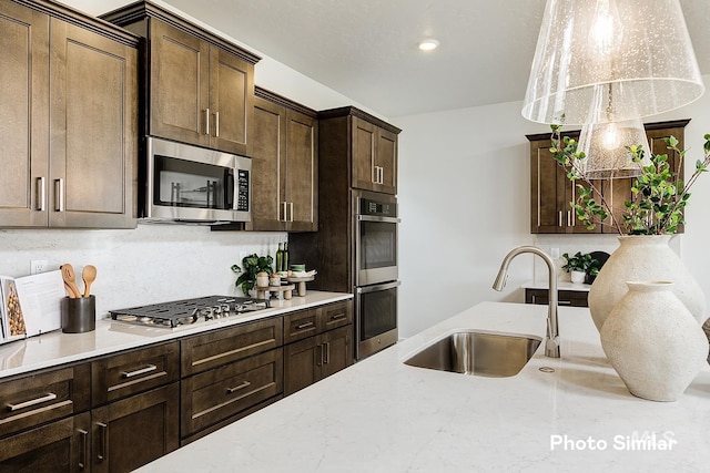 5543 E Bridal Veil Falls Dr, Nampa, ID 83686 - kitchen featuring stainless steel appliances, tasteful backsplash, a sink, dark brown cabinetry, and light stone countertops