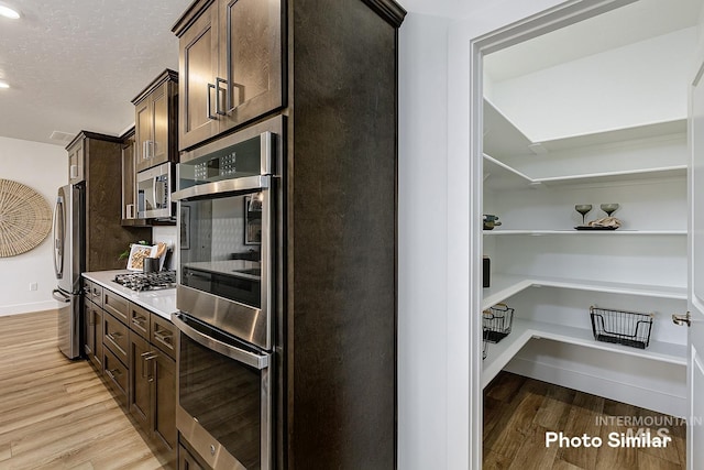 5543 E Bridal Veil Falls Dr, Nampa, ID 83686 - kitchen with appliances with stainless steel finishes, dark brown cabinetry, light wood-style flooring, light countertops, and recessed lighting