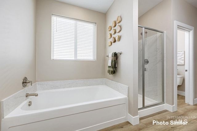 5543 E Bridal Veil Falls Dr, Nampa, ID 83686 - bathroom featuring a stall shower, toilet, a garden tub, wood finished floors, and baseboards
