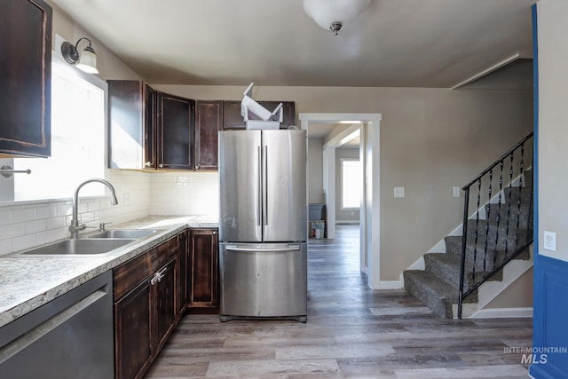 kitchen featuring tasteful backsplash, appliances with stainless steel finishes, light countertops, light wood-style floors, and a sink