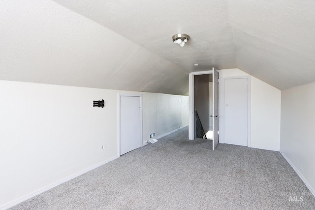 bonus room featuring a textured ceiling, carpet floors, and lofted ceiling