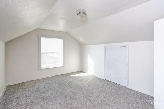 bonus room with carpet floors, vaulted ceiling, a textured ceiling, and baseboards