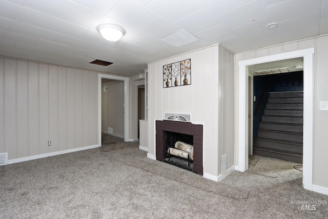 unfurnished living room with a brick fireplace, carpet, stairs, and baseboards