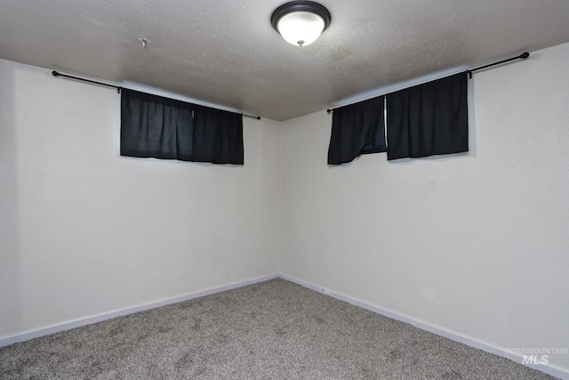 carpeted empty room featuring a textured ceiling and baseboards