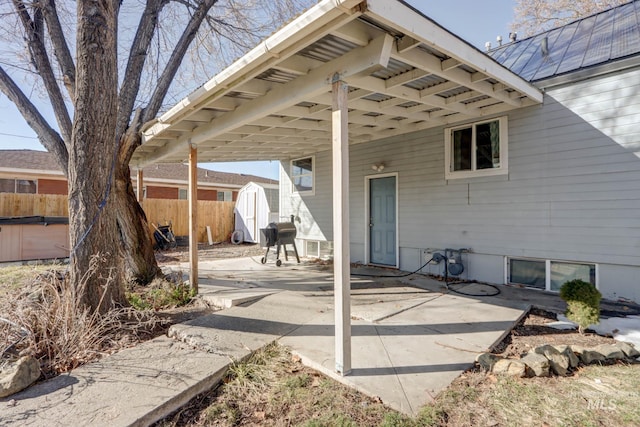 view of patio featuring area for grilling, a shed, an outdoor structure, and fence