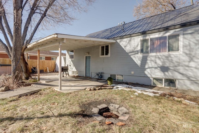 rear view of property featuring a patio area, fence, and metal roof