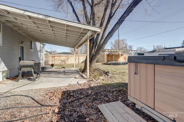 view of yard with driveway, a patio area, a fenced backyard, and an attached carport