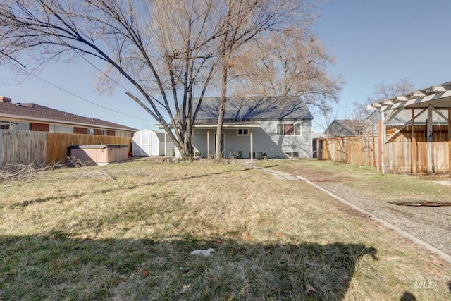 view of yard featuring an outbuilding, a fenced backyard, a storage shed, and a pergola