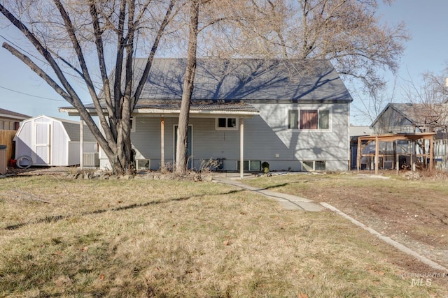 rear view of property with an outbuilding, a yard, and a storage unit