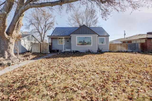 view of front of house with metal roof, board and batten siding, and fence