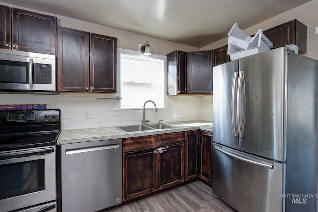 kitchen featuring stainless steel appliances, tasteful backsplash, light countertops, a sink, and dark brown cabinets