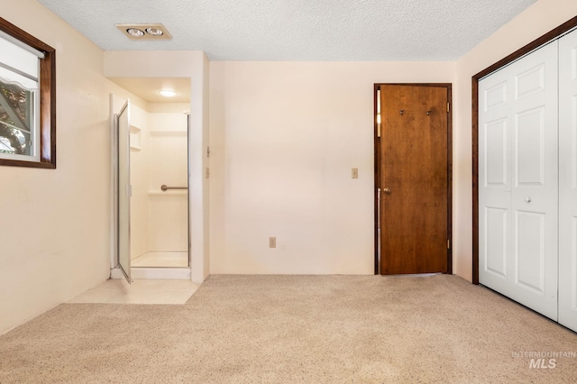 unfurnished bedroom featuring light carpet, a closet, and a textured ceiling