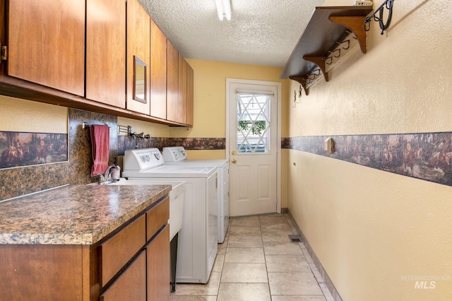 laundry room featuring light tile patterned flooring, cabinets, a textured ceiling, and independent washer and dryer