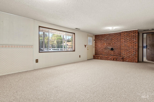 unfurnished living room with carpet, a textured ceiling, and brick wall