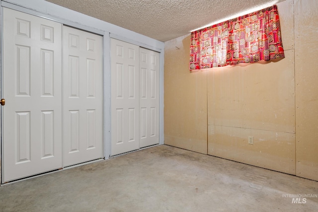 unfurnished bedroom featuring a textured ceiling and two closets