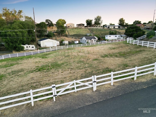 yard at dusk featuring a rural view