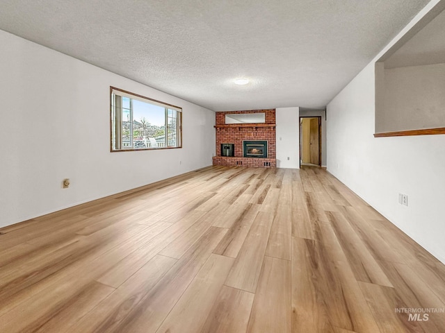 unfurnished living room with a fireplace, light hardwood / wood-style flooring, and a textured ceiling