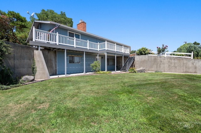 back of property with a deck and a yard